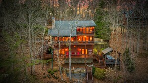 Ein mehrstöckiges Blockhaus mit Steinsschornstein, Holzterrasse und Whirlpool.