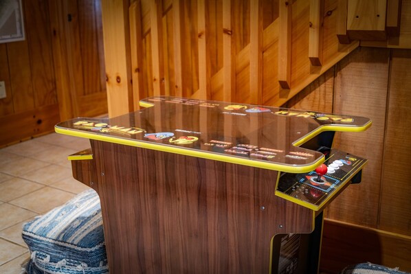 A wooden arcade machine with a glass top and colorful game icons. - Johnny's Lakeside Hideaway - Private Dock | Hot Tub | Game Room (Morganton)