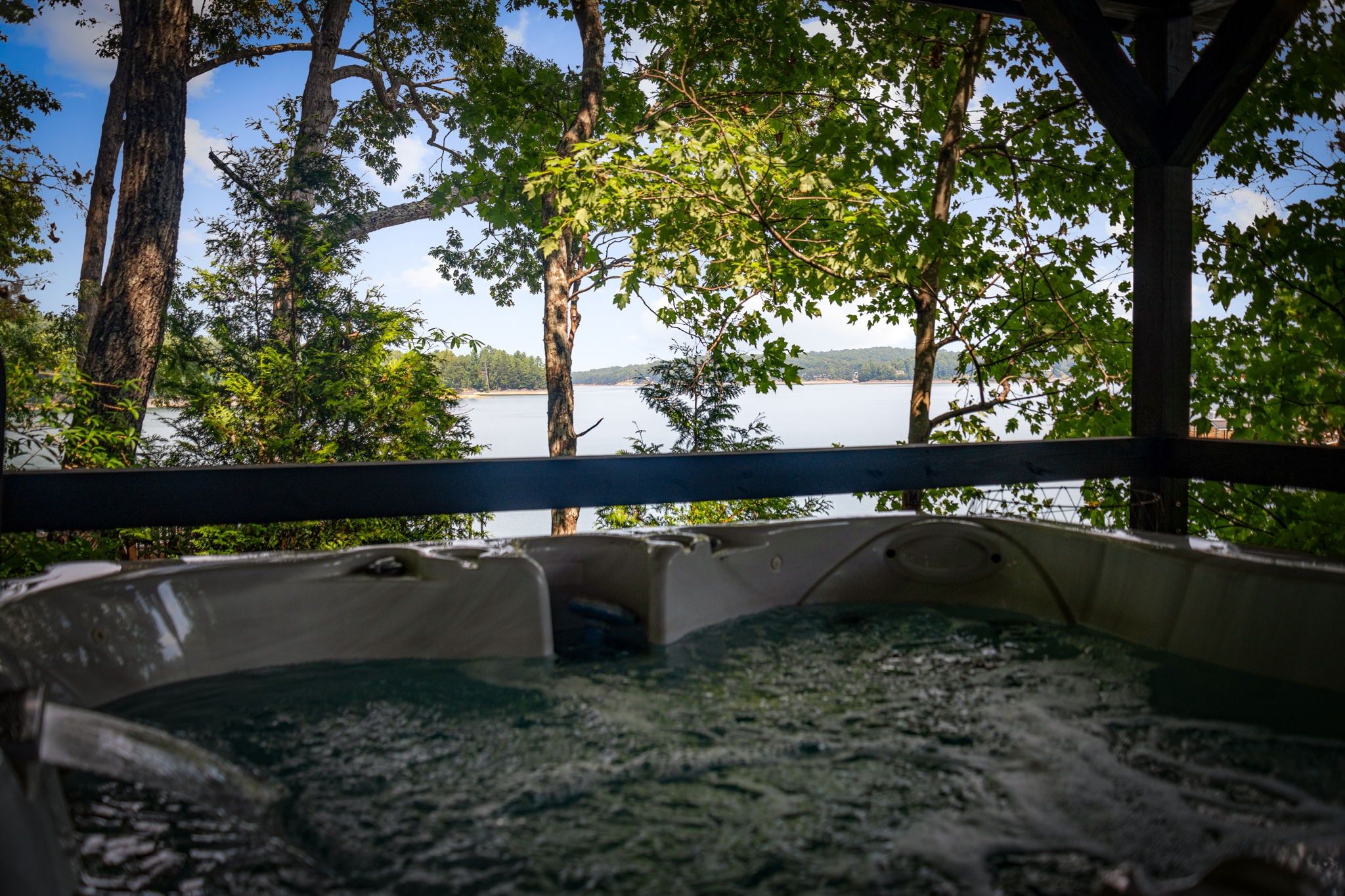 A hot tub surrounded by trees and a lake view.
