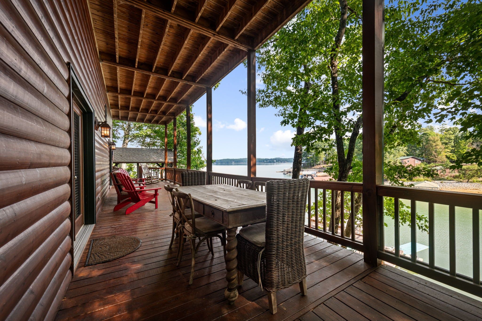 Une terrasse en bois avec une table et des chaises, donnant sur une étendue d’eau.