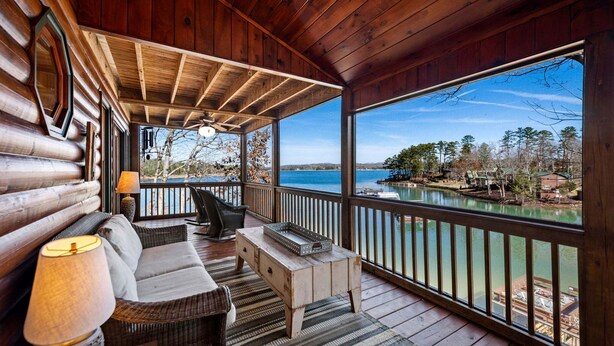 Eine Holzhütte mit Veranda, einer Couch, einer Lampe und Blick auf einen See.