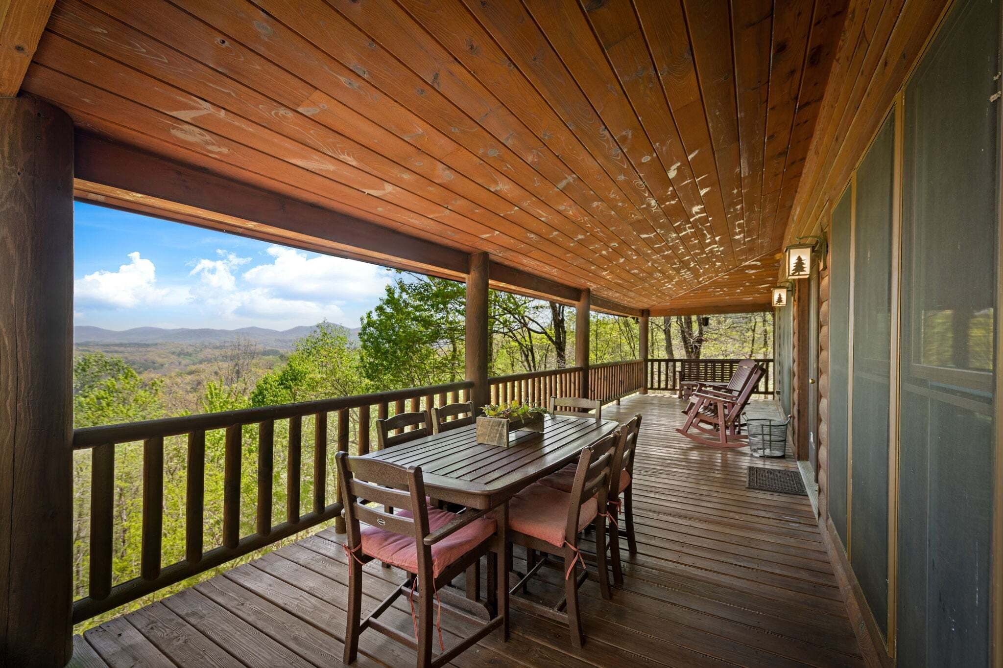 A wooden deck with a table and chairs, overlooking a mountainous landscape.