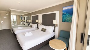 A hotel room with three beds, a round wooden table, and a large mirror. - Central Located 2 Double-bed Hotel Room in Surfers (Surfers Paradise)