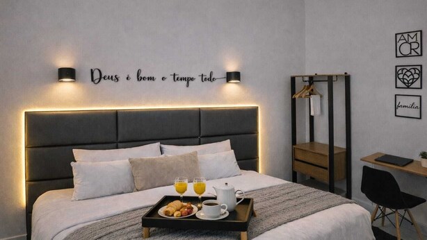 A modern hotel room with a bed, bedside table, desk, and a wall with motivational quotes. - Practical and cozy house in Vila Velha (2 guests) (Vila Velha)