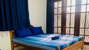 Ein Zimmer mit einem Einzelbett, einem Holzstuhl und einem Fenster mit Metallgitter.