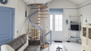 Ein Wohnzimmer mit einer geschwungenen Treppe, einem Sofa, einem Couchtisch und einem Schrank.