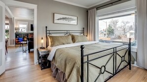 Quarto com cama, ventilador de teto, janela com cortinas e vista para o exterior.
