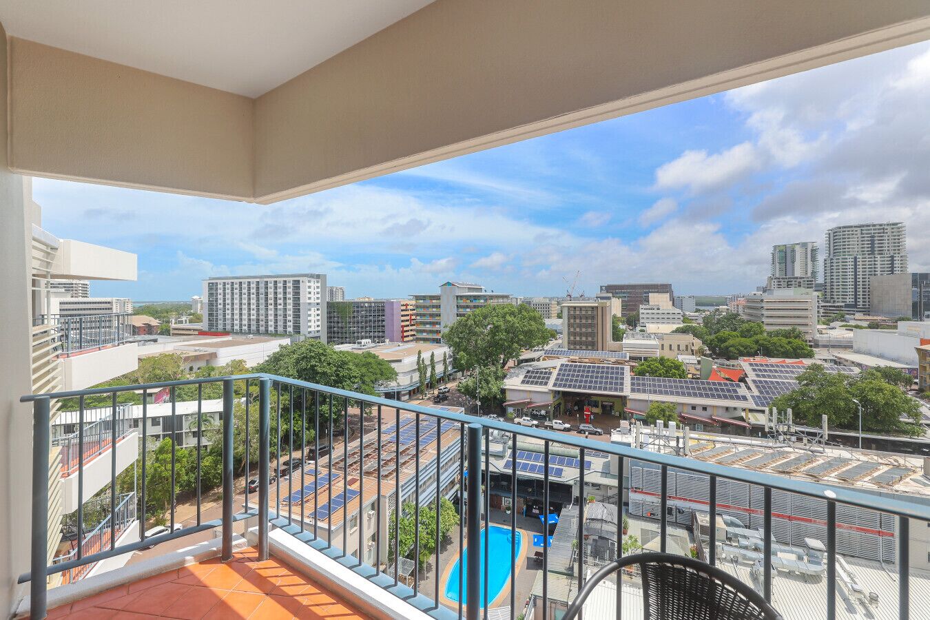 Un balcon offrant une vue sur le paysage urbain, avec des bâtiments et une piscine.