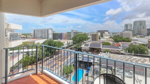 A balcony with a view of a cityscape, including buildings and a swimming pool. - Top Floor Tropical Escape | Pool | King Bed | Balcony (Darwin City)
