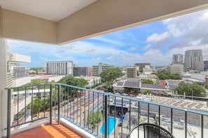 A balcony with a view of a cityscape, including buildings and a swimming pool. - Top Floor Tropical Escape | Pool | King Bed | Balcony (Darwin City)
