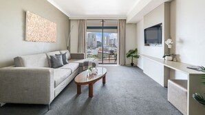 A modern living room with a sofa, coffee table, and a TV mounted on the wall. - Top Floor Tropical Escape | Pool | King Bed | Balcony (Darwin City)