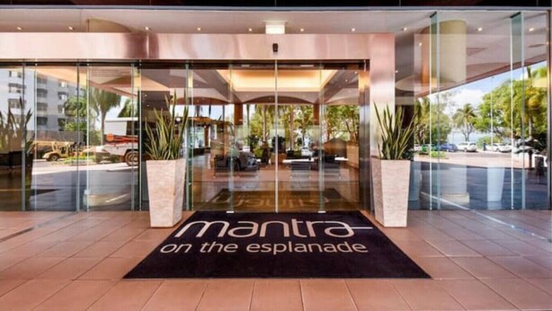 A hotel entrance with a glass facade, a black mat with the text "mantra on the esplanade," and potted plants on either side. - Top Floor Tropical Escape | Pool | King Bed | Balcony (Darwin City)