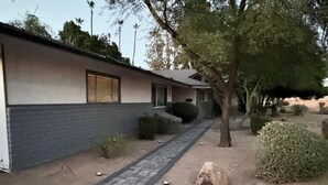 A building with a brick facade, a paved walkway, and a tree. - Golf House Retreat-Newly Remodeled 4BR (Tempe)
