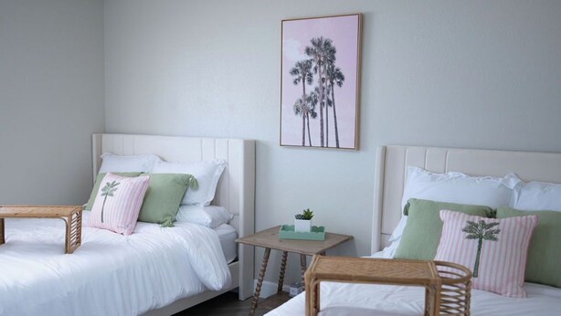 A hotel room with two beds, a small table, and a wall-mounted picture. - Golf House Retreat-Newly Remodeled 4BR (Tempe)