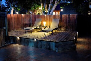 An outdoor deck with two lounge chairs and a table, surrounded by a wooden fence. - Golf House Retreat-Newly Remodeled 4BR (Tempe)