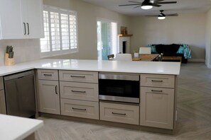 A modern kitchen with a large island, built-in appliances, and a dining area with a sofa. - Golf House Retreat-Newly Remodeled 4BR (Tempe)