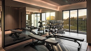 A gym with exercise equipment, large windows, and a view of a building.