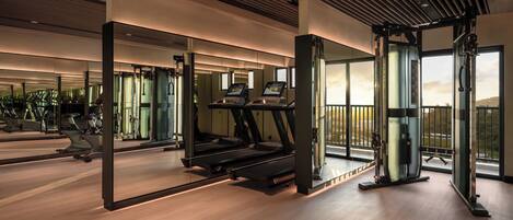 A gym with treadmills, weight machines, and a large mirror.
