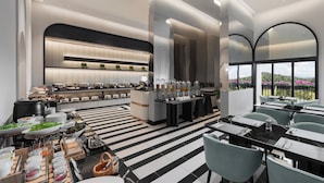 A modern hotel lobby with a buffet, seating area, and large windows offering a view.