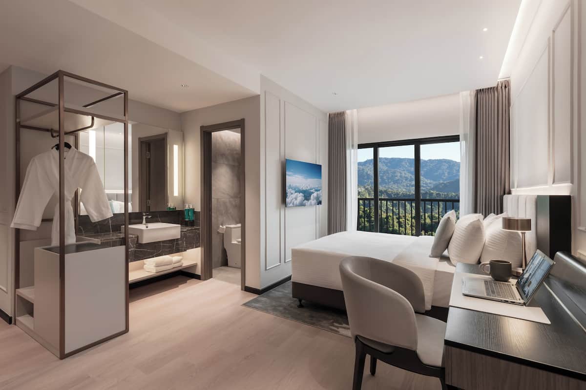 A modern hotel room with a bed, desk, and bathroom.