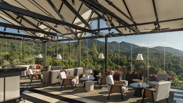 A modern outdoor lounge area with a checkered floor, seating arrangements, and a view of mountains.