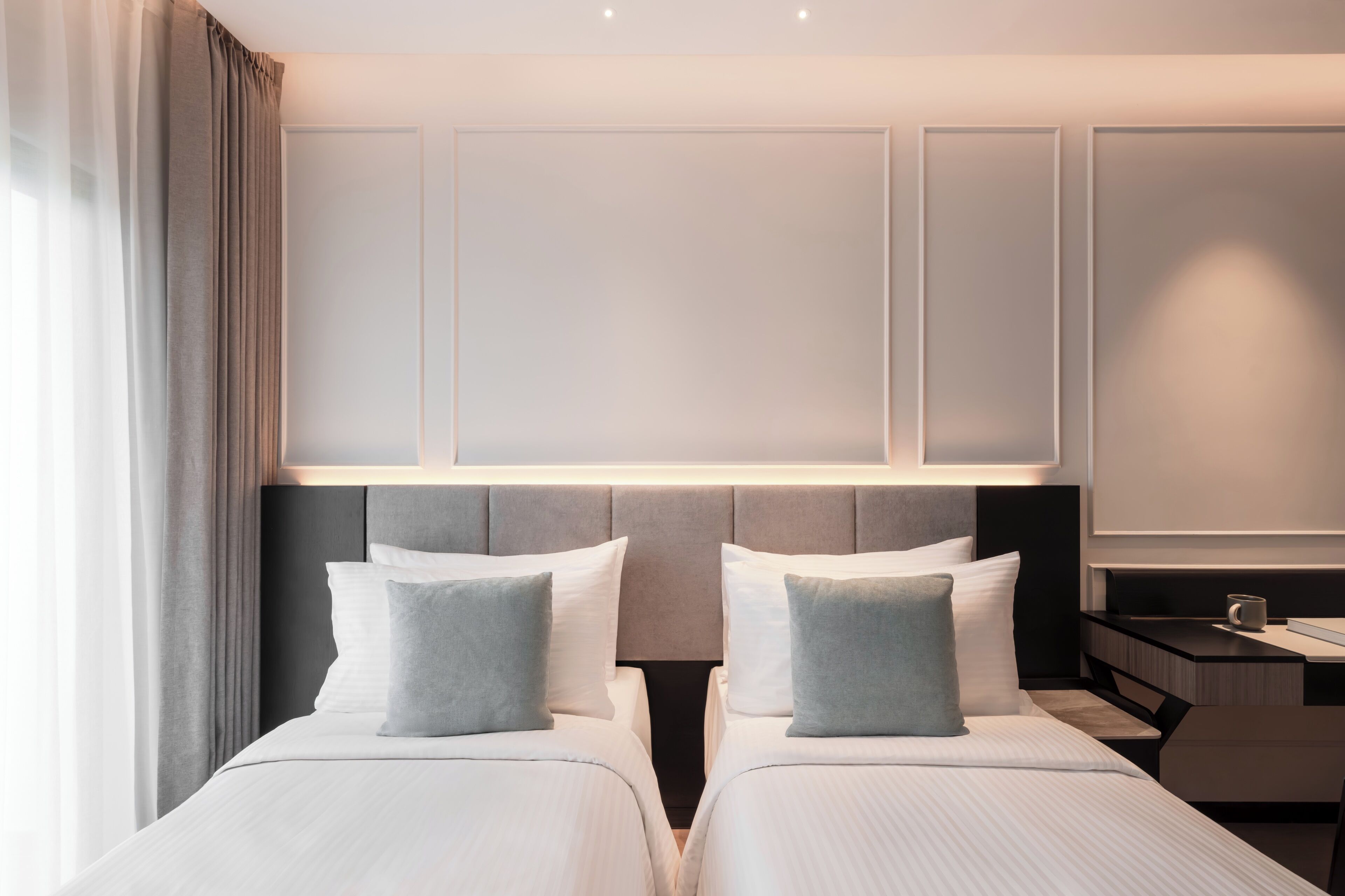 A hotel room with two beds, a nightstand, and a lamp.