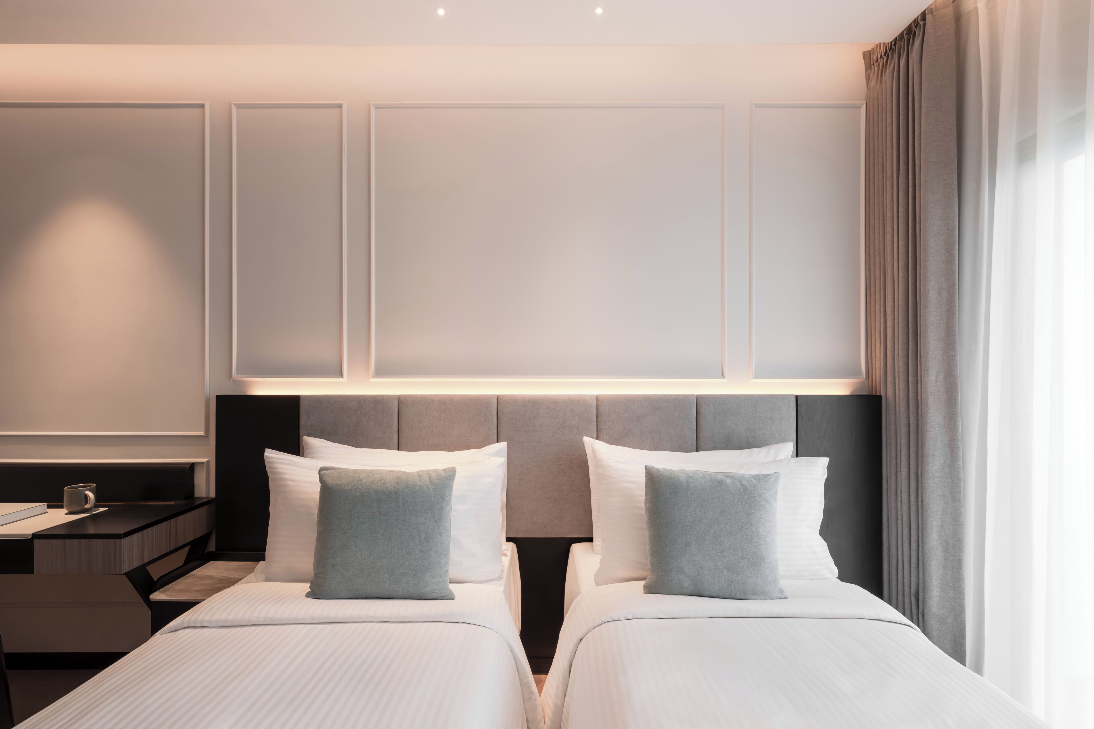 Une chambre d’hôtel avec deux lits, une table de chevet et une commode.