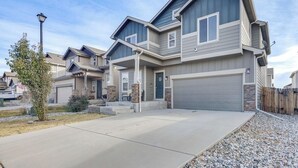 A modern residential building with a garage, a front porch, and a landscaped driveway.
