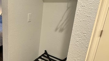 A small laundry area with a drying rack and a shelf.