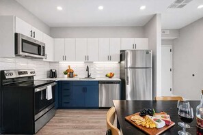 Een moderne keuken met witte en blauwe kasten, roestvrijstalen apparatuur en een eethoek met een gedekte tafel.