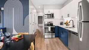 Eine moderne Küche mit Edelstahlgeräten, ein Essbereich mit dunklem Tisch und einem außergewöhnlichen Schwarz-Weiß-Wanddesign.