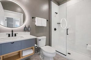 Une salle de bain moderne avec un lavabo, des toilettes et une douche à parois de verre.