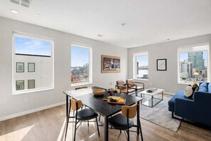 Una sala de estar moderna con comedor, ventanas amplias y vista a la ciudad.