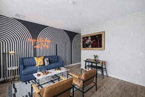 Una sala de estar moderna con un sofá azul, una mesa de centro y una zona de comedor con sillas.