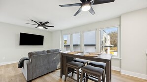 Une cuisine moderne avec un coin repas, un ventilateur de plafond et une grande fenêtre donnant sur l’extérieur.