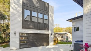 Une maison moderne à deux étages, dotée d’un garage et d’un escalier menant à un deuxième niveau.