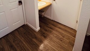 A bathroom with a wooden floor, a white door, and a wooden countertop with a sink. - 16 - Scenic route stays (Challenge-Brownsville)