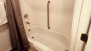 A bathroom with a white bathtub, a shower curtain, and a towel rack. - 16 - Scenic route stays (Challenge-Brownsville)