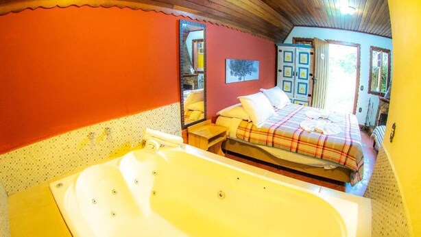 Una stanza con una vasca da bagno ampia, un letto con coperta a quadri e un soffitto in legno.