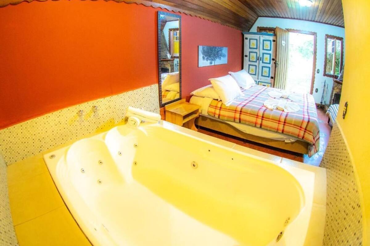 Una habitación con una bañera grande, una cama con manta escocesa y techo de madera.