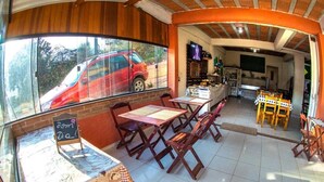 Un accogliente caffè con arredi in legno, una lavagna con il menu e vista su un'auto rossa all'esterno.