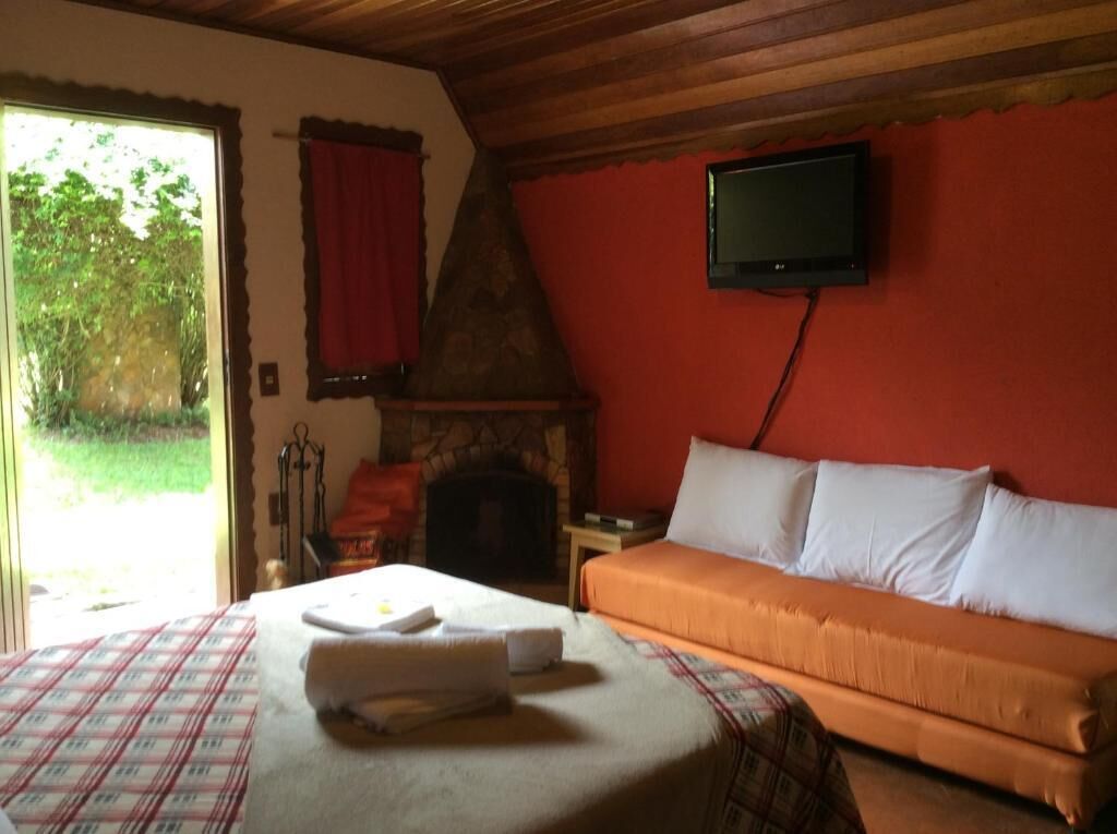 Una habitación con cama, sofá, chimenea y televisor.