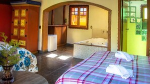 A hotel room with a bed, a bathtub, a small desk, and a wardrobe. - Villa da Vila (Monte Verde)