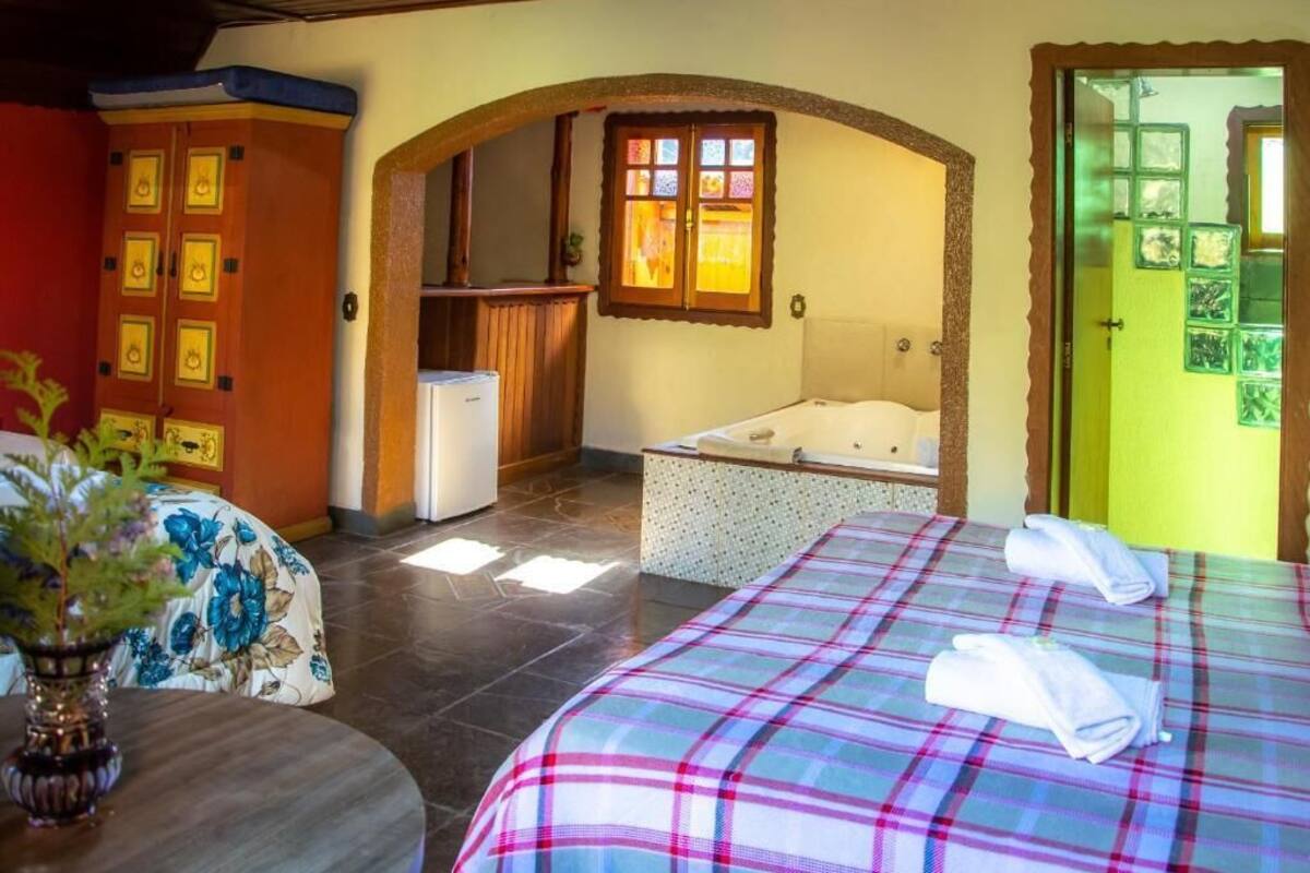 Una habitación de hotel con cama, bañera, escritorio pequeño y armario.
