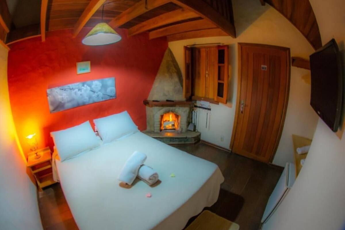 Un dormitorio con cama, chimenea, techo de madera y televisor.