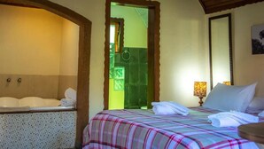 A hotel room with a bed, a bathroom with a bathtub, and a shower area. - Villa da Vila (Monte Verde)