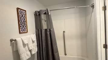 A bathroom with a shower, a towel rack, and a framed picture on the wall.