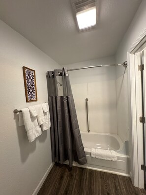 A bathroom with a shower, a towel rack, and a framed picture on the wall. - 23 - Friends, Family, Fun (Challenge-Brownsville)