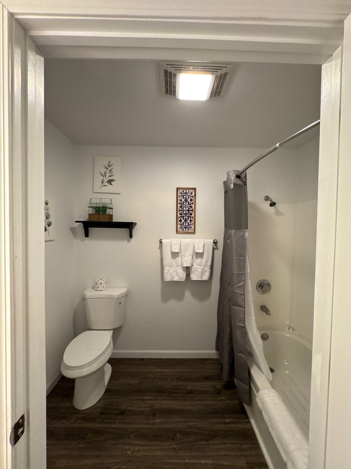 A bathroom with a toilet, a shower, and a bathtub. There are two towels hanging on the wall.