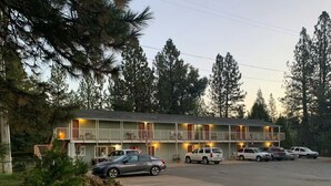 Motel amb diverses plantes, un aparcament i un paisatge forestal de fons.